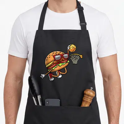 Tablier de cuisine noir avec un hamburger anthropomorphe en lunettes de soleil effectuant un tir au panier.