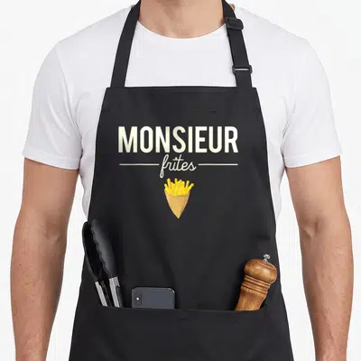 Tablier de cuisine noir avec inscription Monsieur Frites et illustration de patates frites dans un papier kraft.