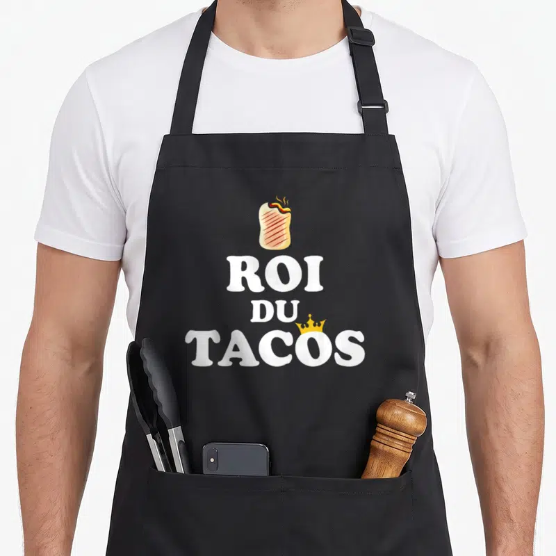 Tablier de cuisine noir avec un burrito fumant surplombant le texte Roi du Tacos en blanc et une couronne dorée.