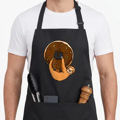 Tablier de cuisine noir avec un fourreau tenant un donut au chocolat et des perles colorées.