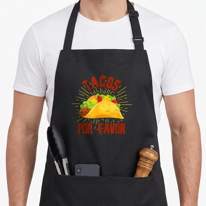 Tablier de cuisine noir avec une illustration de taco coloré et le texte Tacos Por Favor en rouge.