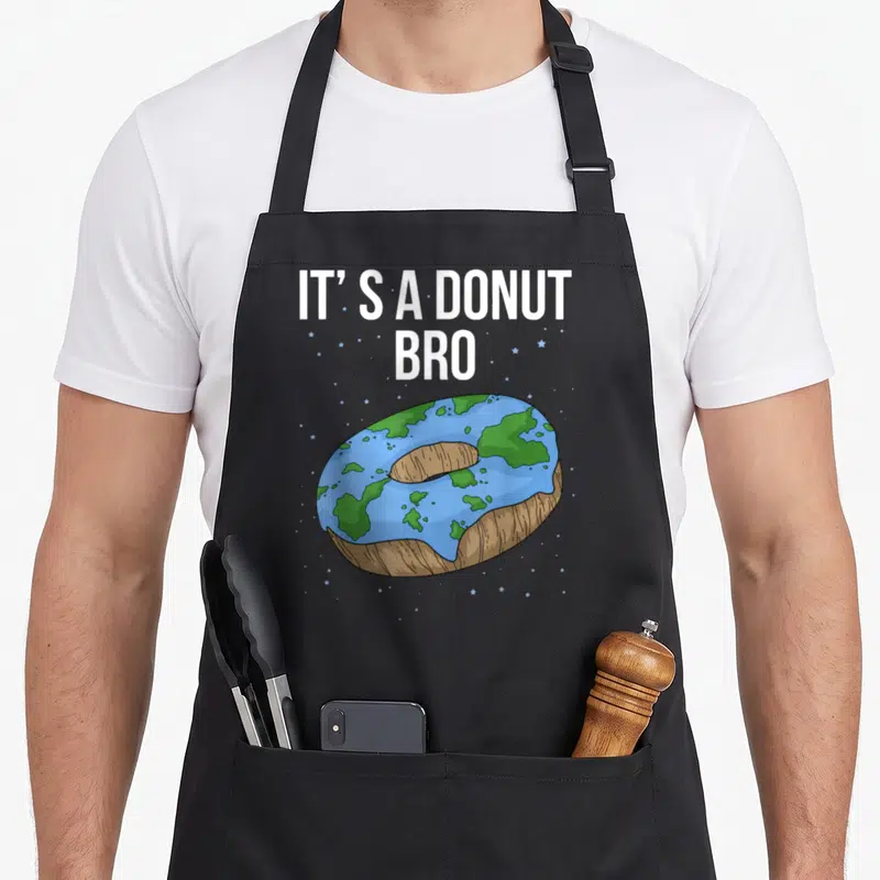 Tablier de cuisine noir avec une illustration d'une Terre en donut et le texte It's a donut bro sur fond d'étoiles.