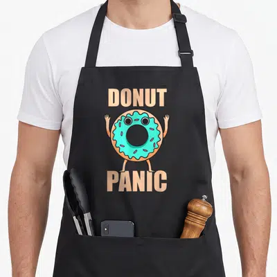 Tablier de cuisine noir avec un donut anthropomorphe turquoise levant les bras sous le texte Donut Panic