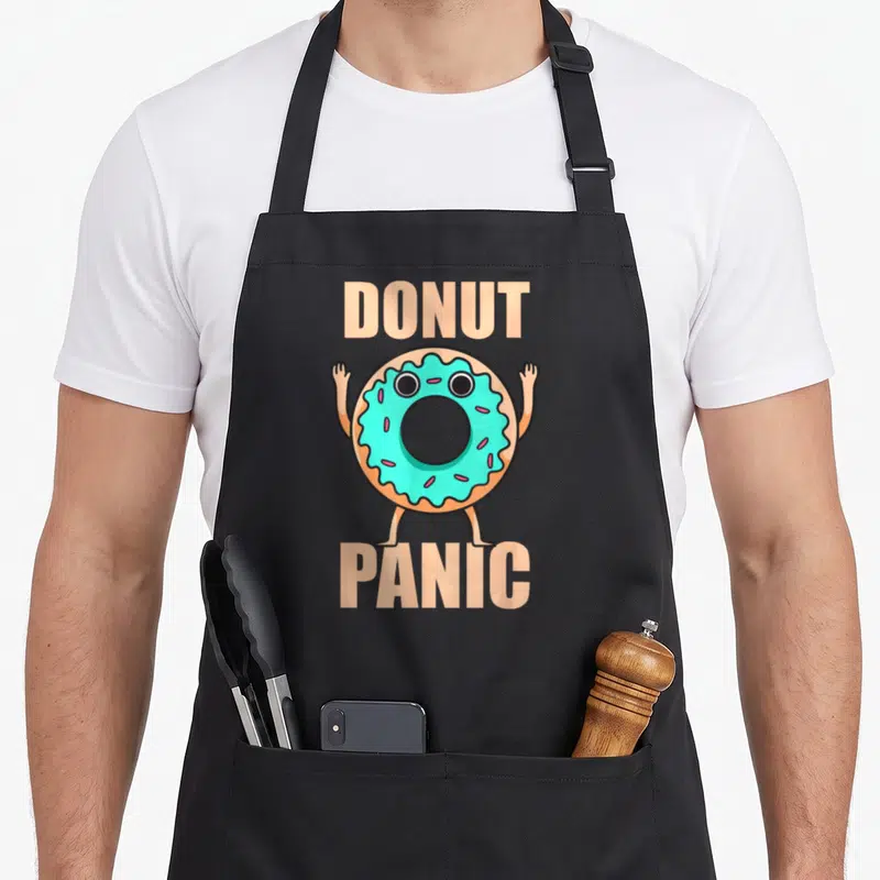 Tablier de cuisine noir avec un donut anthropomorphe turquoise levant les bras sous le texte Donut Panic