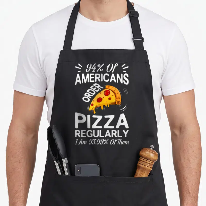 Tablier de cuisine noir avec une part de pizza et le texte 94% of Americans order pizza regularly en blanc.