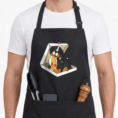 Tablier de cuisine noir avec un Bouvier Bernais mangeant une pizza dans une boîte blanche.