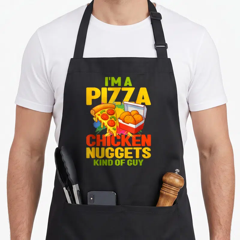 Tablier de cuisine noir avec une illustration colorée d'une pizza et de croquettes de poulet dans une boîte.