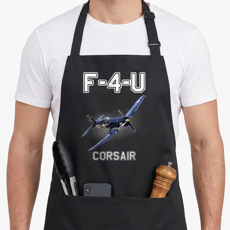 Tablier de cuisine noir avec illustration d'un avion F-4-U Corsair bleu en vol et texte blanc F-4-U Corsair.