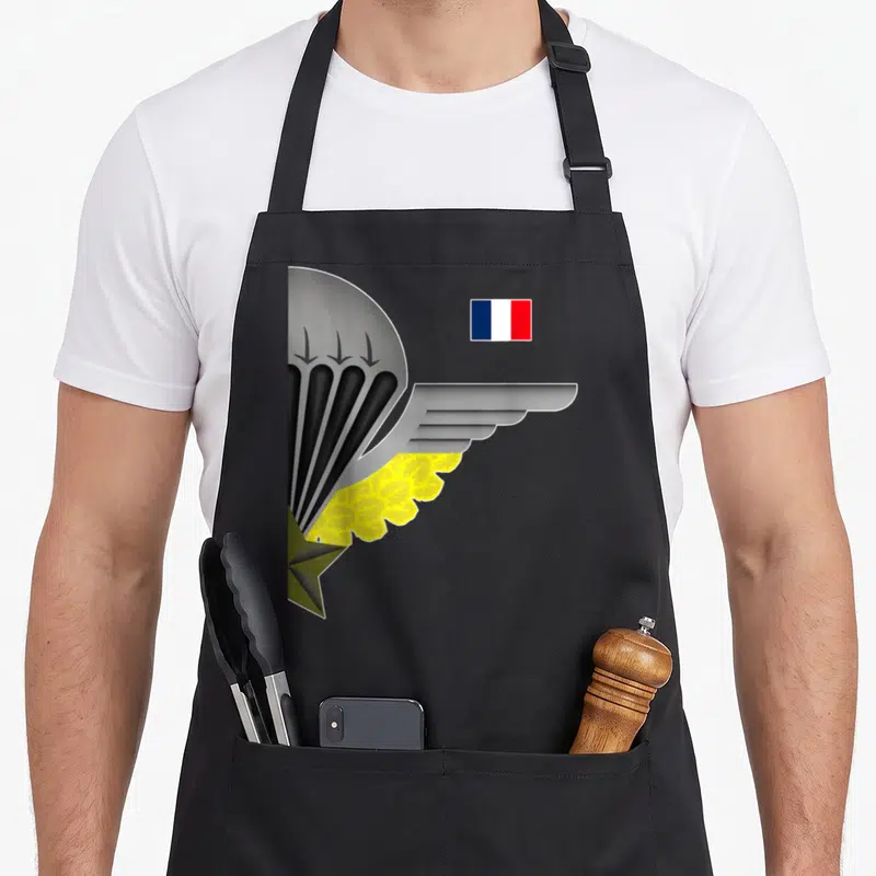 Tablier de cuisine noir avec une aile parachutiste, une étoile verte et le drapeau français en haut à droite.