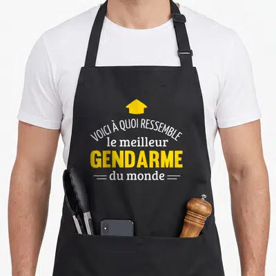 Tablier de cuisine noir avec inscription Voici à quoi ressemble le meilleur gendarme du monde et une flèche jaune pointant vers le haut.