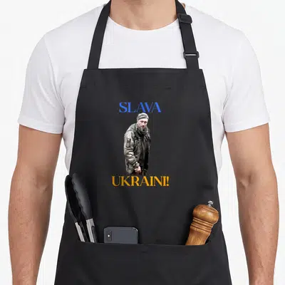 Tablier de cuisine noir avec illustration d'un soldat en uniforme et texte Slava Ukraini imprimé en bleu et orange.