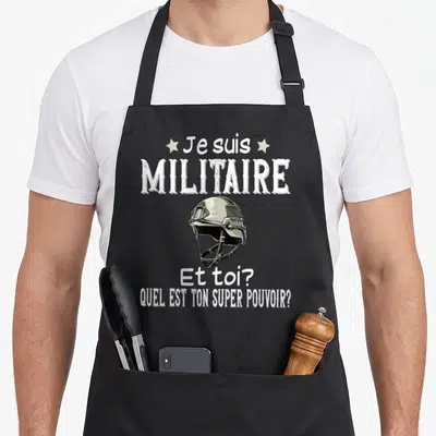 Tablier de cuisine noir avec illustration de casque militaire et texte blanc humoristique sur fond uni.