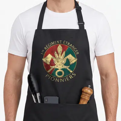 Tablier de cuisine noir avec l'insigne circulaire du 1er Régiment Étranger Pionniers en rouge, vert et or.