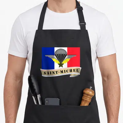 Tablier de cuisine noir avec l'emblème Saint-Michel Parachutiste sur fond de drapeau français aux couleurs vives.