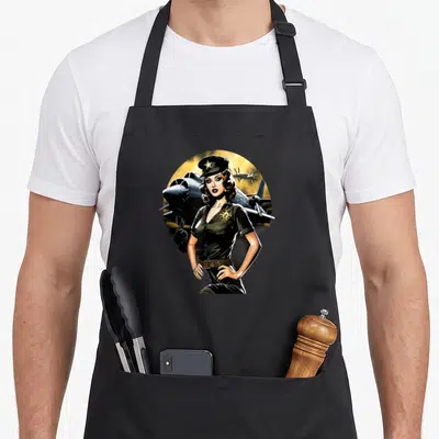 Tablier de cuisine noir avec une illustration de pinup en uniforme d'aviation militaire devant un avion de chasse vintage.