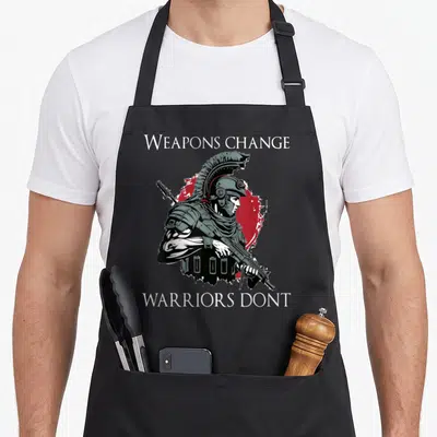 Tablier de cuisine noir avec illustration d'un soldat spartiate et le texte Weapons change warriors dont en blanc sur fond rouge.