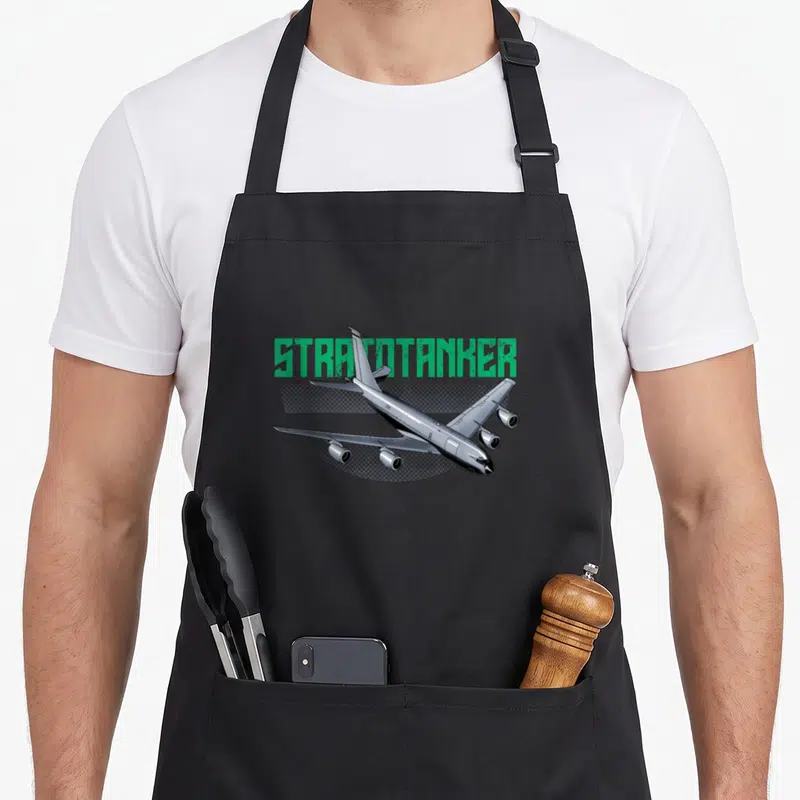 Tablier de cuisine noir avec illustration d'avion Stratotanker et texte vert stylisé.