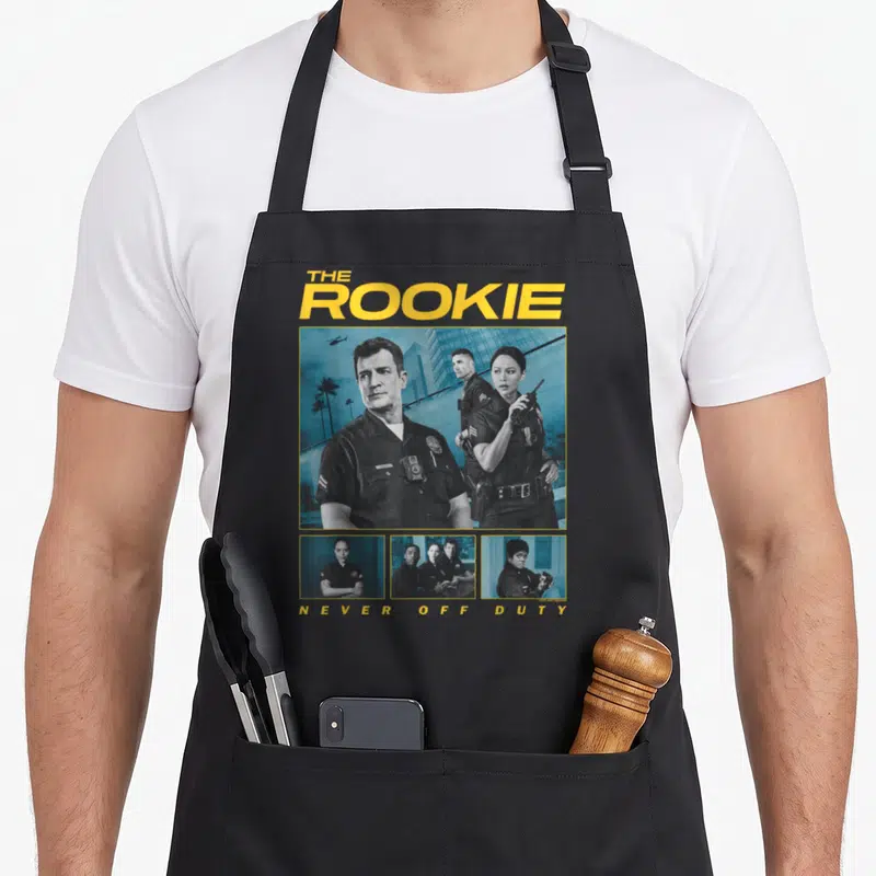 Tablier de cuisine noir avec collage de personnages en uniforme et texte jaune The Rookie Never Off Duty.