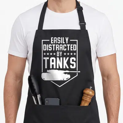 Tablier de cuisine noir avec inscription EASILY DISTRACTED BY TANKS et silhouette de char blindé en blanc.