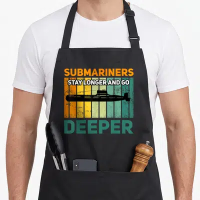 Tablier de cuisine noir avec illustration vintage d'un sous-marin et texte orange vert sur fond rayé.