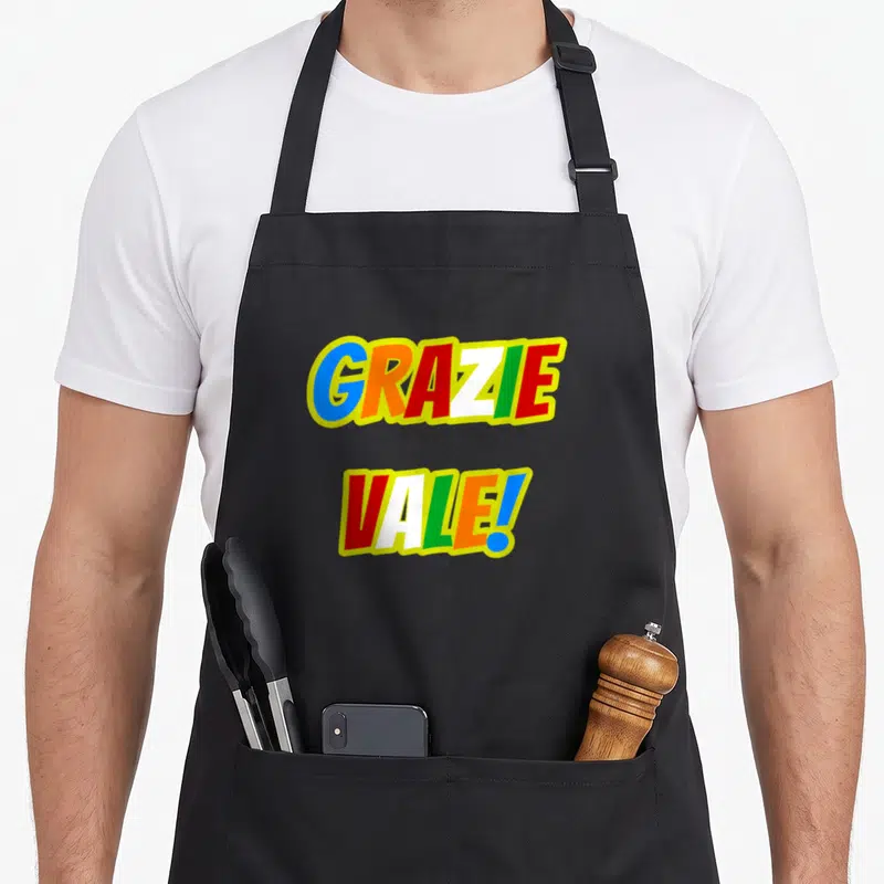 Tablier de cuisine noir avec l'inscription Grazie Vale en lettres colorées style jeu de lettres.