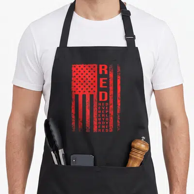 Tablier de cuisine noir avec drapeau rouge stylisé et texte vertical RED DEPLOYED MY BOY RED imprimé en centre.