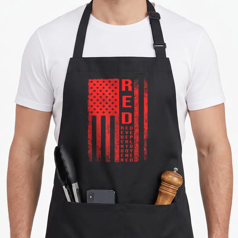 Tablier de cuisine noir avec drapeau rouge stylisé et texte vertical RED DEPLOYED MY BOY RED imprimé en centre.