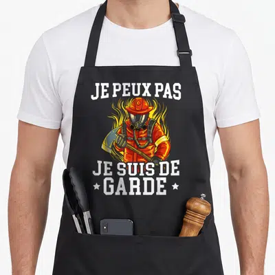 Tablier de cuisine noir avec illustration d'un pompier en tenue orange et texte blanc Je peux pas je suis de garde