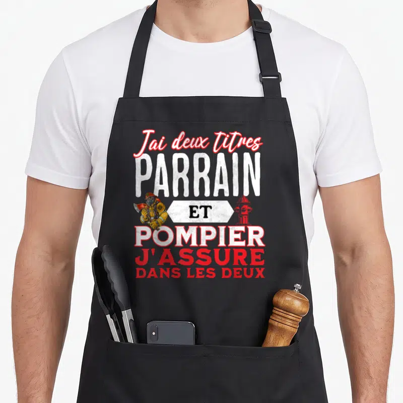 Tablier de cuisine noir avec inscription parrain pompier et illustration d'un sapeur-pompier tenant une hache.
