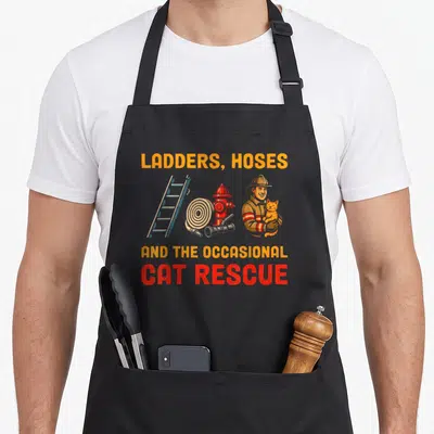 Tablier de cuisine noir avec illustration de pompier tenant un chat et l'inscription CAT RESCUE en rouge.