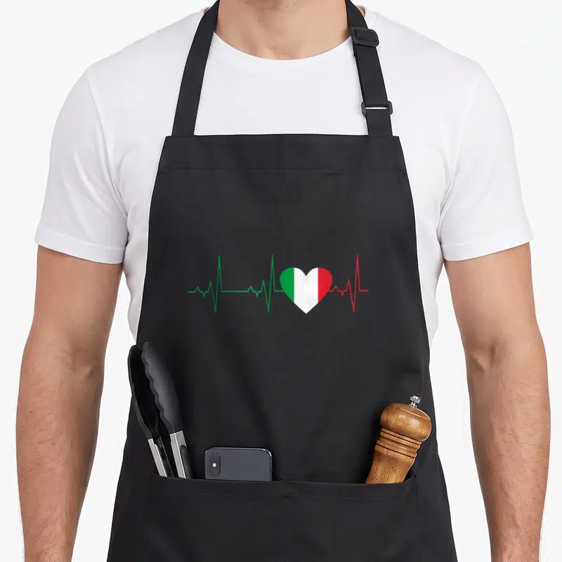 Tablier de cuisine noir avec un cœur tricolore italien surmonté d'une ligne d'électrocardiogramme stylisée.