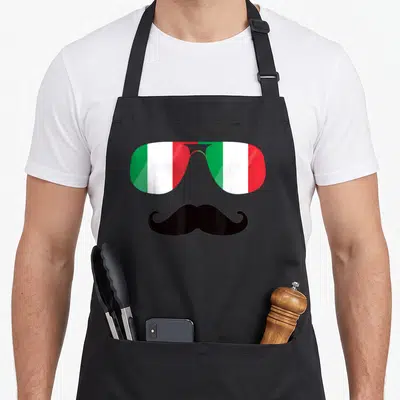 Tablier de cuisine noir avec lunettes aux verres tricolores verts blancs rouges et moustache noire courbée sous les verres.