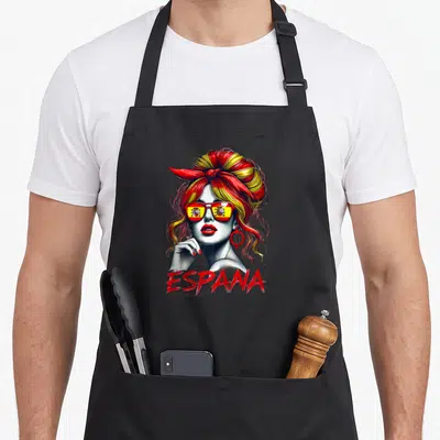 Tablier de cuisine noir avec une femme au chignon rouge et jaune portant des lunettes au drapeau espagnol et le mot ESPANA.