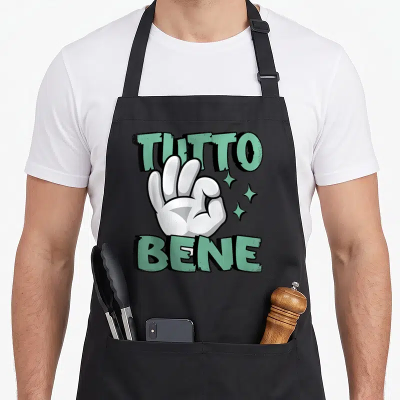 Tablier de cuisine noir avec illustration main blanche gesture tutto bene texte vert et étoiles scintillantes sur fond uni.