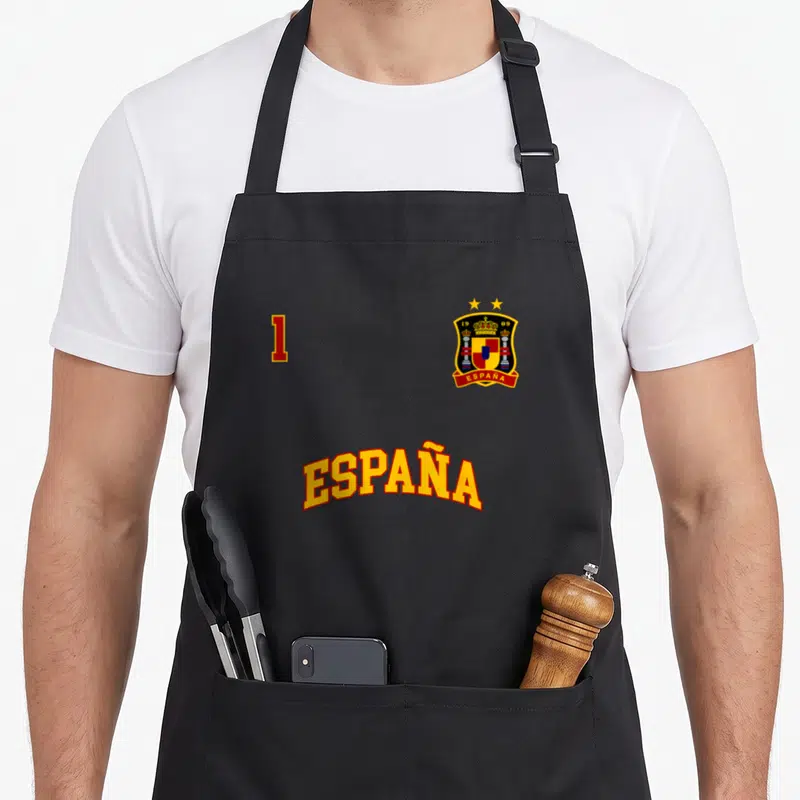 Tablier de cuisine noir avec le mot España, le chiffre 1 et un blason aux couleurs espagnoles surmonté de deux étoiles dorées.