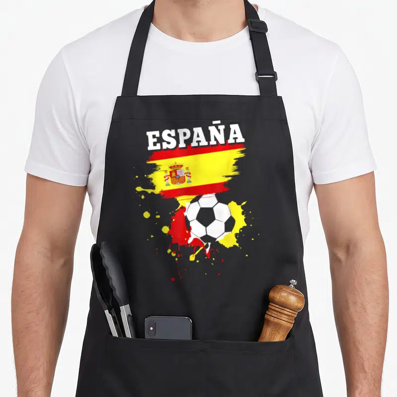 Tablier de cuisine noir avec illustration drapeau Espagne, ballon de foot et éclaboussures de peinture rouge et jaune.