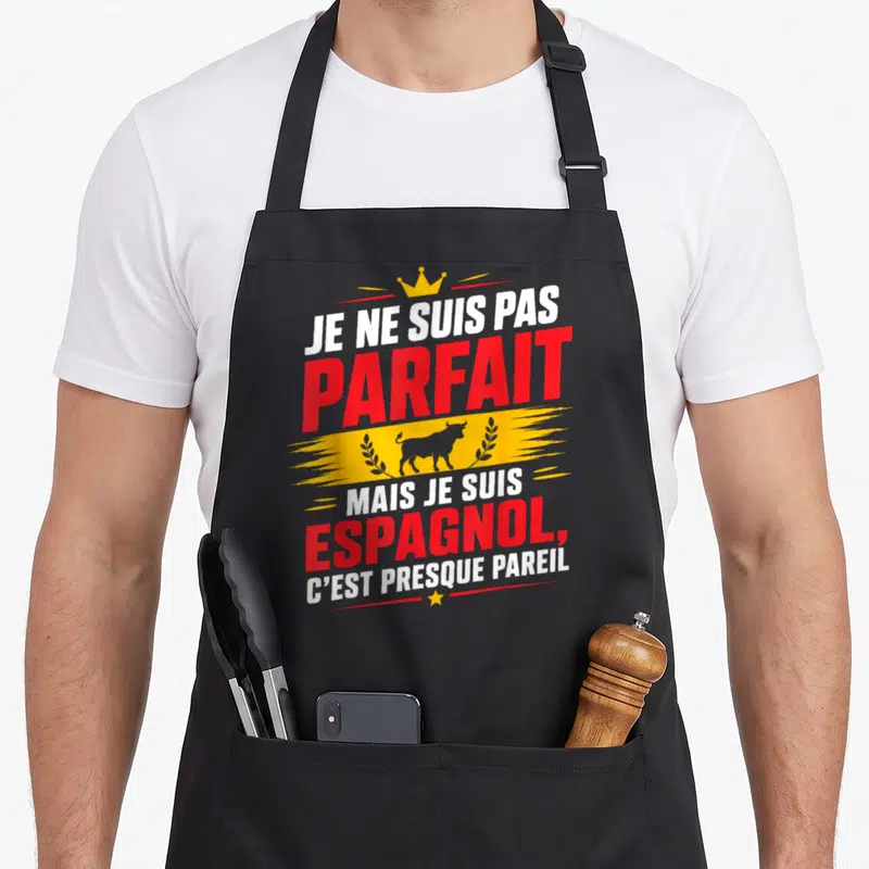 Tablier de cuisine noir avec l'inscription Je ne suis pas parfait mais je suis Espagnol surmonté d'une couronne et d'un taureau gris.