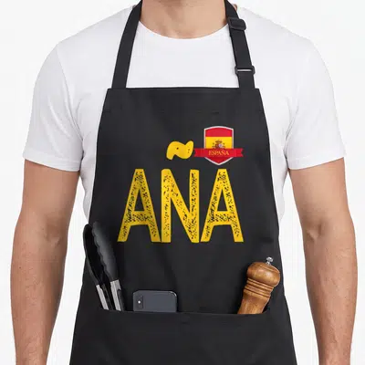 Tablier de cuisine noir avec le nom ANA en grandes lettres jaunes et un écusson rouge à l'effigie de l'Espagne.