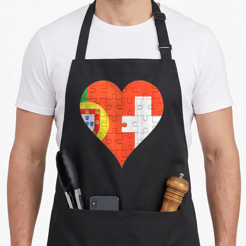 Tablier de cuisine noir avec un grand cœur formé par les drapeaux du Portugal et de la Suisse en motif puzzle.