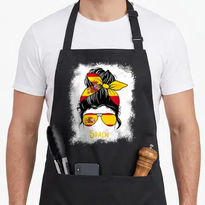 Tablier de cuisine noir avec une femme aux cheveux noirs, un bandana et des lunettes aux couleurs de l'Espagne et le mot Spain.