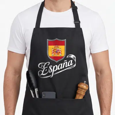 Tablier de cuisine noir avec l'écusson royal espagnol et le mot España en écriture cursive blanche sous le blason.