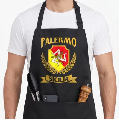 Tablier de cuisine noir avec le blason de Palerme, l'inscription Sicilia et une triskèle dorée sur fond rouge et jaune.