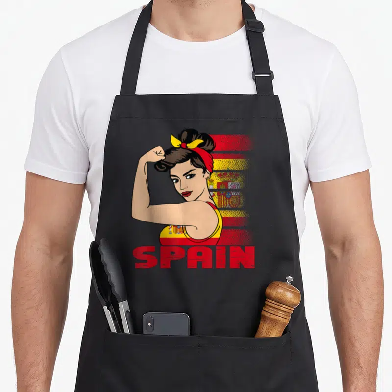 Tablier de cuisine noir avec illustration d'une femme musclée aux couleurs de l'Espagne et le texte SPAIN en rouge.