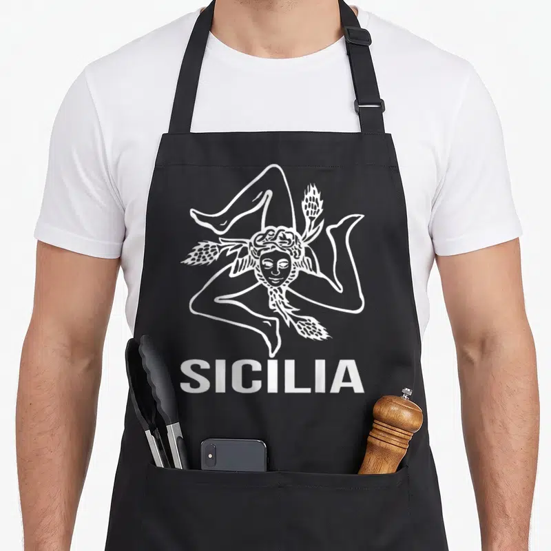 Tablier de cuisine noir avec le symbole blanc de la Trinacria et le texte SICILIA en bas.