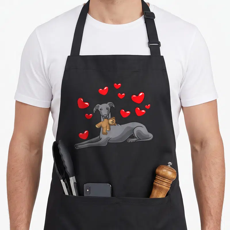 Tablier de cuisine noir avec illustration d'un lévrier italien tenant une peluche et des cœurs rouges flotants.