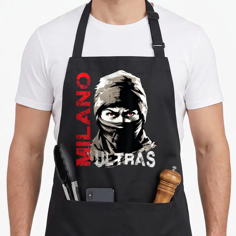 Tablier de cuisine noir avec un visage masqué aux yeux rouges et le texte MILANO ULTRAS imprimé en lettres verticales.
