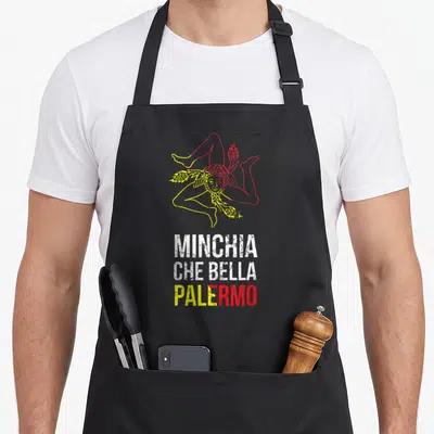 Tablier de cuisine noir avec illustration colorée d'une Trinacria et le texte Minchia Che Bella Palermo en blanc, jaune et rouge.