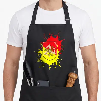 Tablier de cuisine noir avec le blason rouge et jaune de la Sicile représentant la Trinacria et des éclaboussures artistiques.