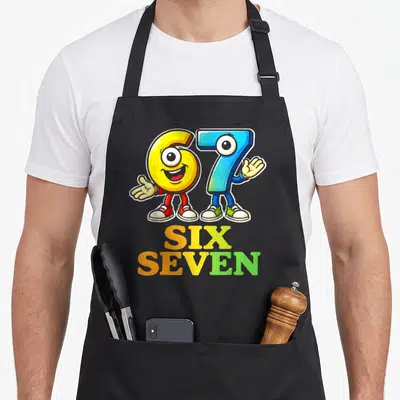 Tablier de cuisine noir avec les chiffres 6 et 7 en personnages colorés et le texte Six Seven imprimé en dessous.