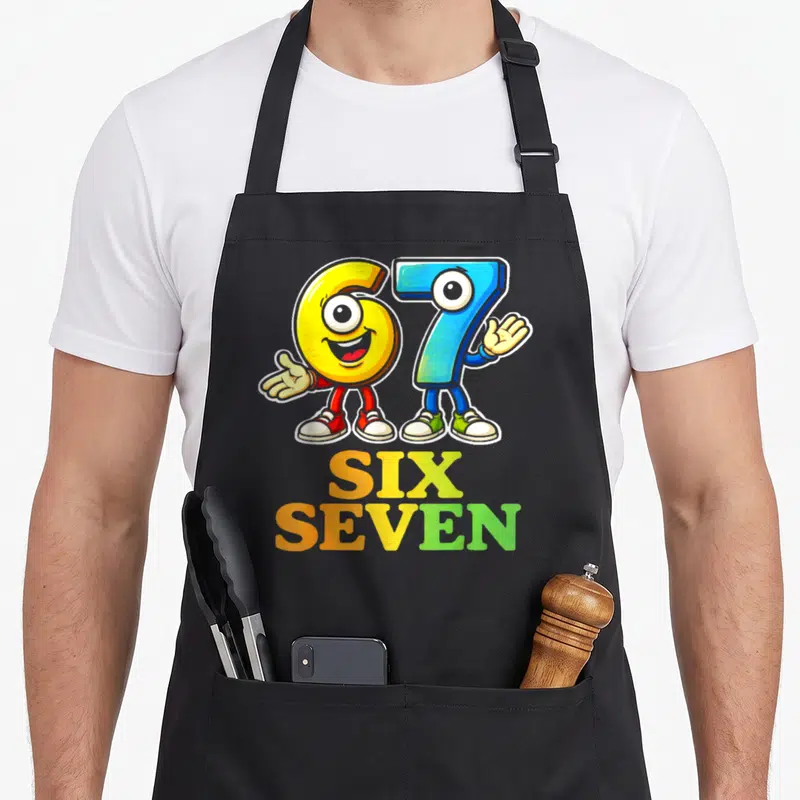Tablier de cuisine noir avec les chiffres 6 et 7 en personnages colorés et le texte Six Seven imprimé en dessous.